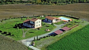 An aerial view of a property with a main house, a swimming pool, and a smaller building, surrounded by green fields and a stone wall. - Apartment 'Azzurro La Valle Del Sole' with Mountain View and Wi-Fi (Castiglione dʼOrcia)