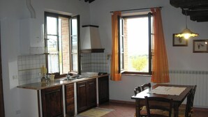 Una cocina con ventana, una mesa de comedor y una lámpara colgante.