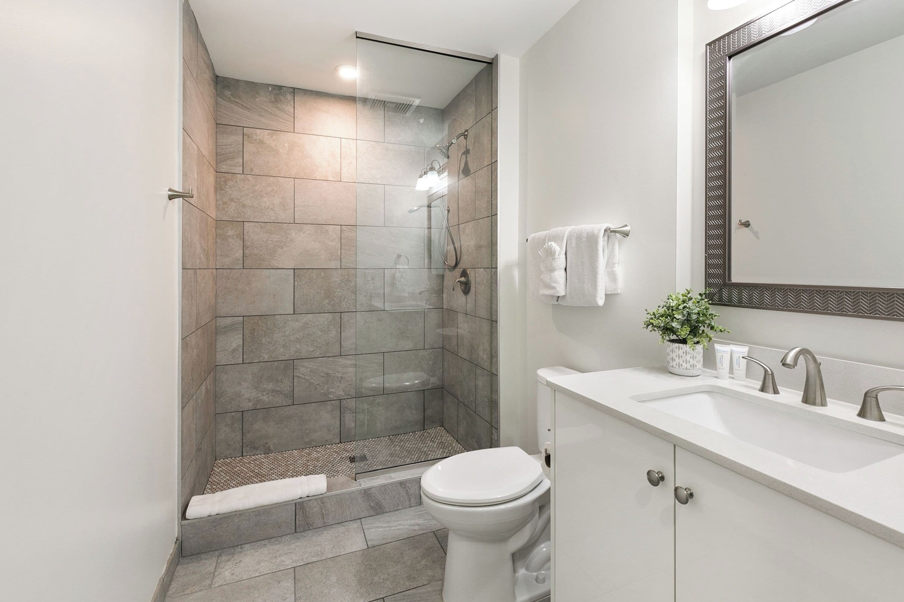 Une salle de bain moderne équipée d’une douche, de toilettes, d’un lavabo et d’un grand miroir.