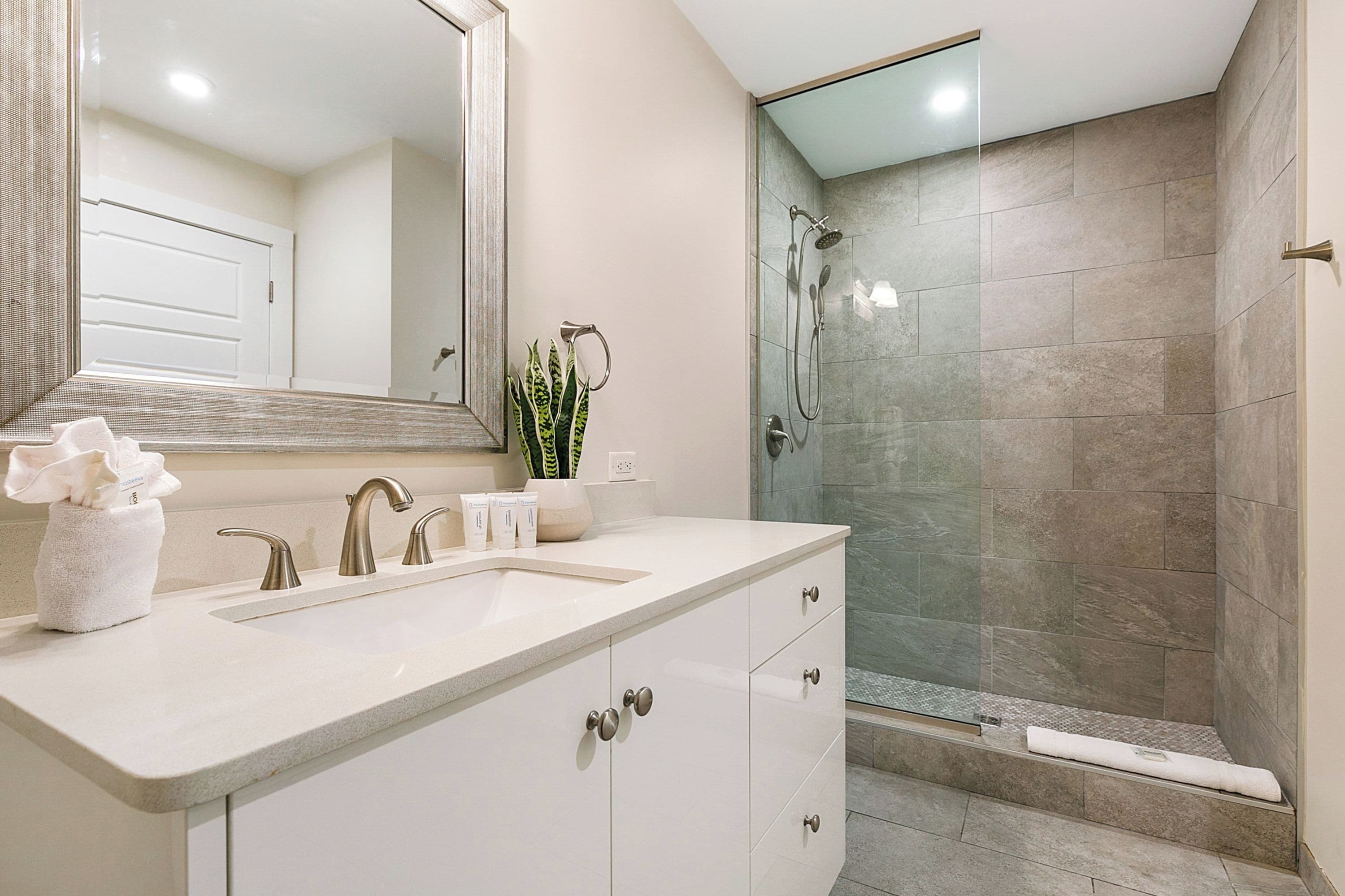 Un baño moderno con un espejo grande, un lavabo y una zona de ducha.
