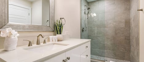 Un baño moderno con un espejo grande, un lavabo y una zona de ducha.