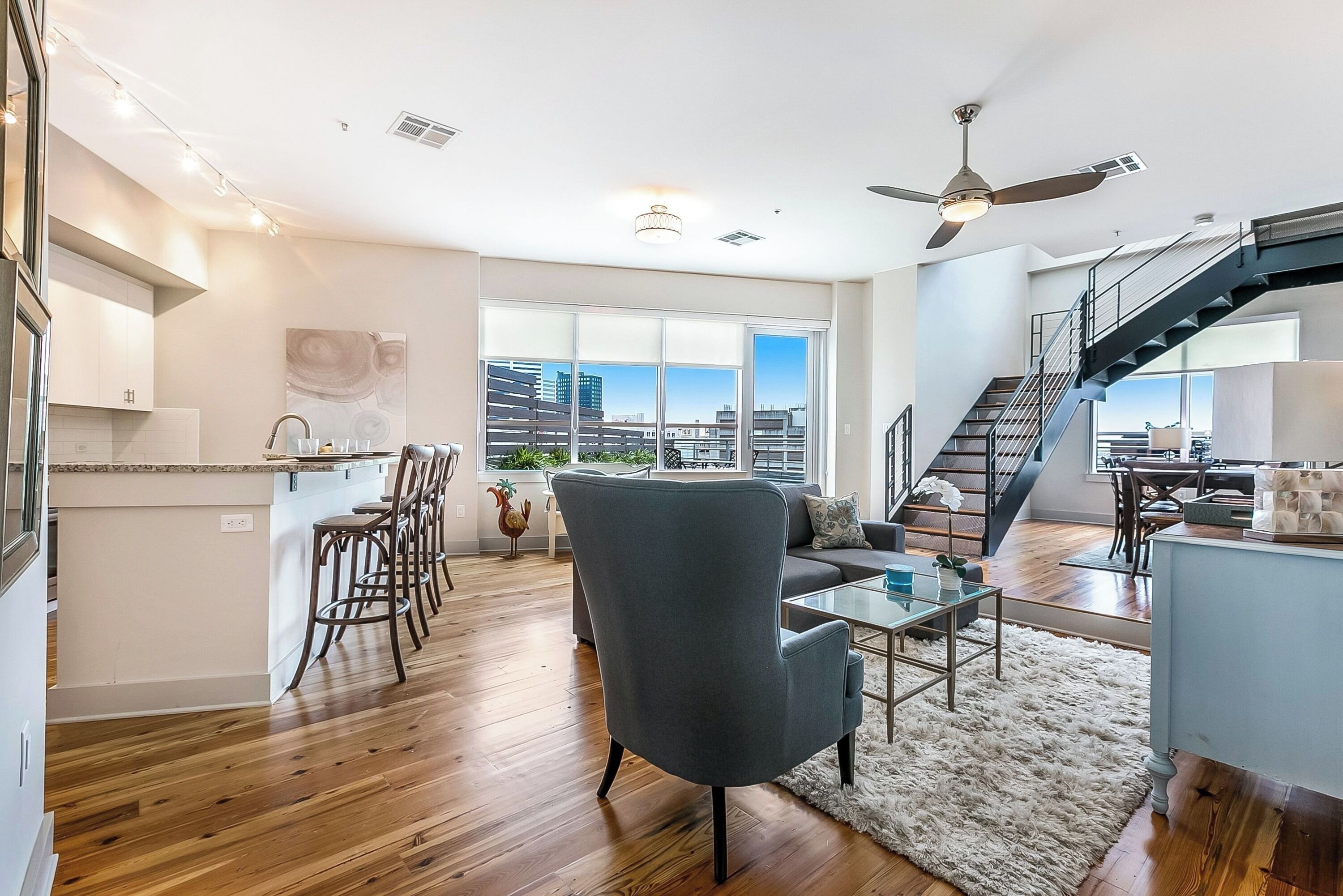 A spacious living area with a modern kitchen, a dining area, and a staircase leading to an upper floor.