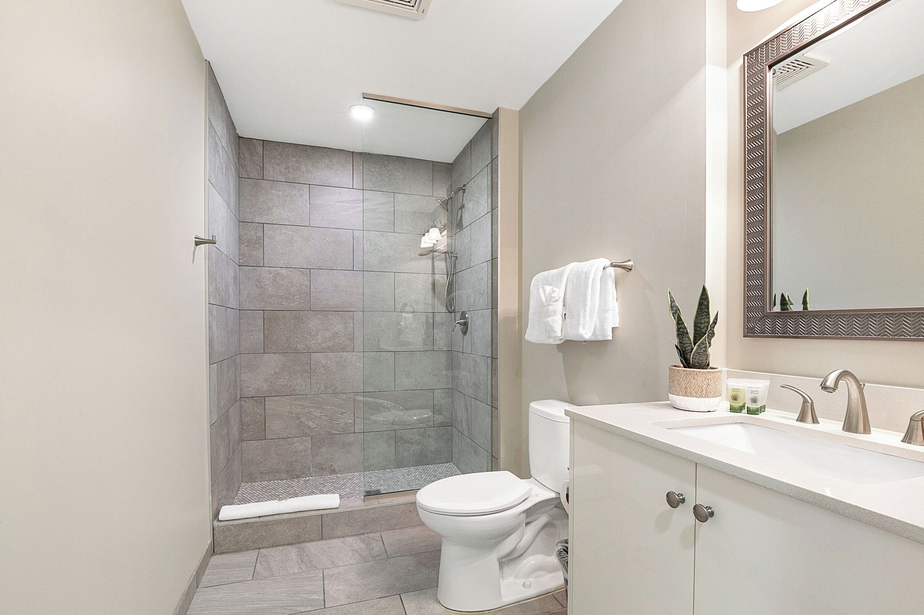 Een moderne badkamer met douche, toilet, wastafel en spiegel.