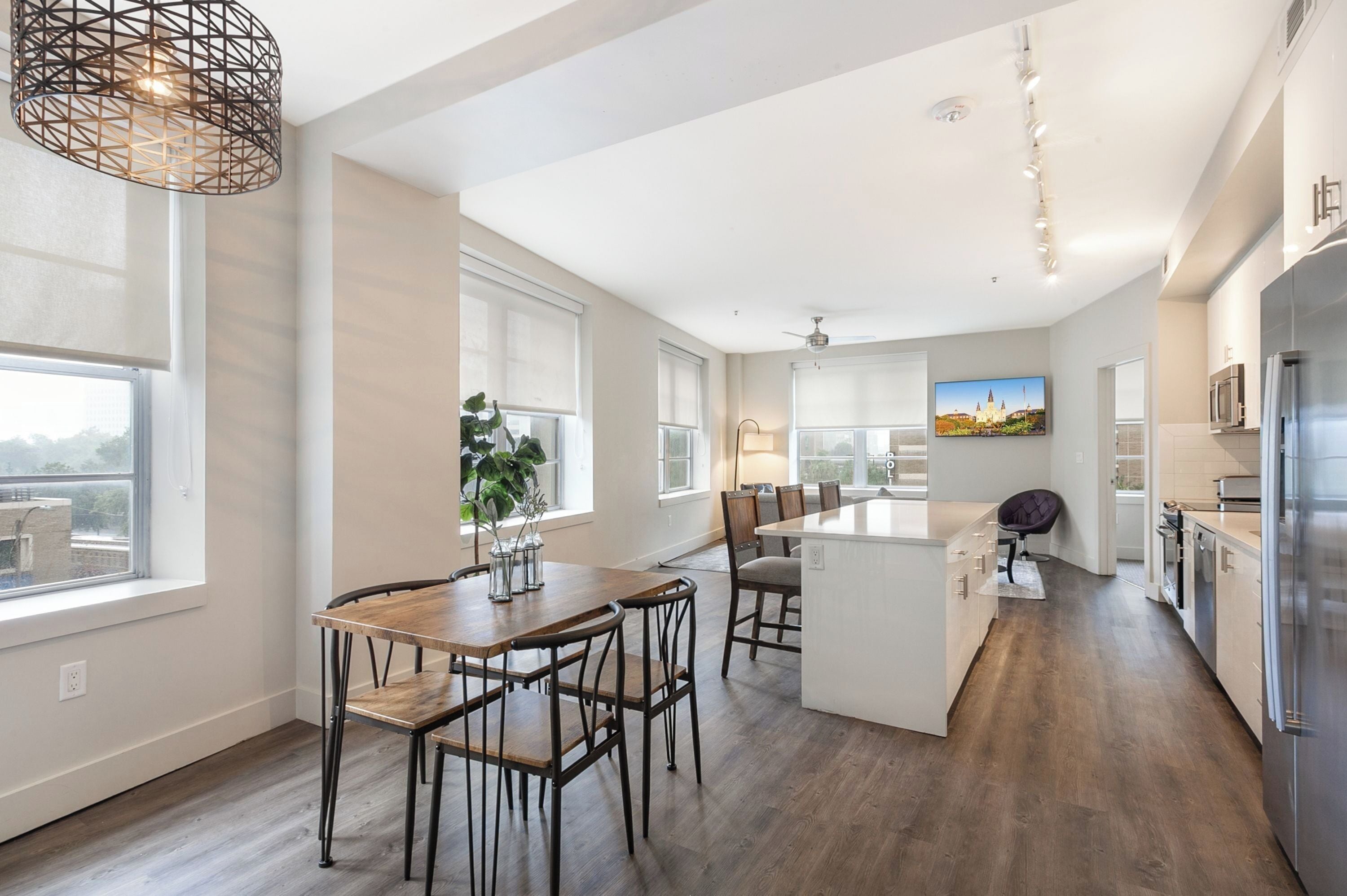 A modern kitchen with a central island, wooden dining table, and chairs.