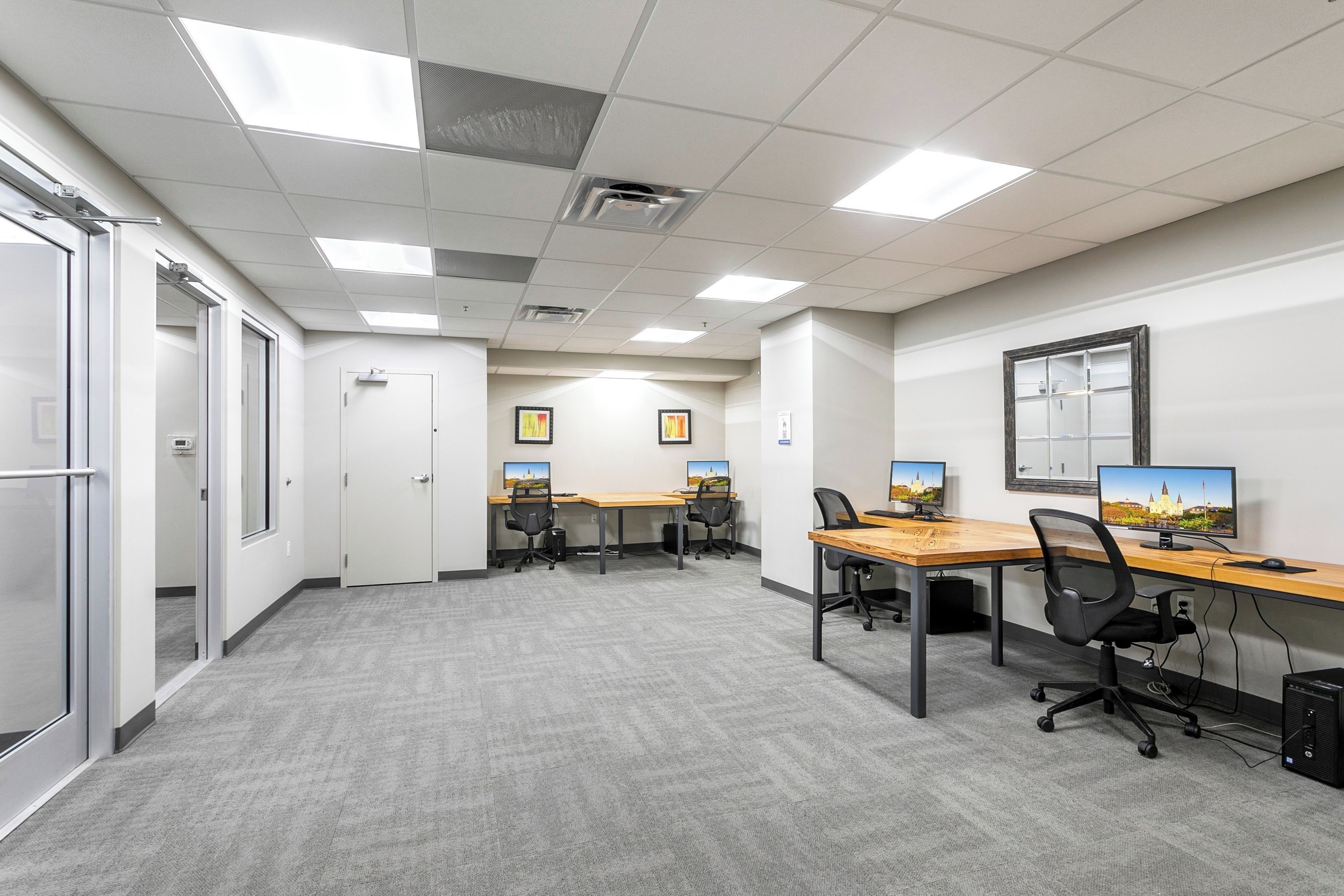 Un espace de bureau moderne doté de plusieurs bureaux, chaises et ordinateurs.