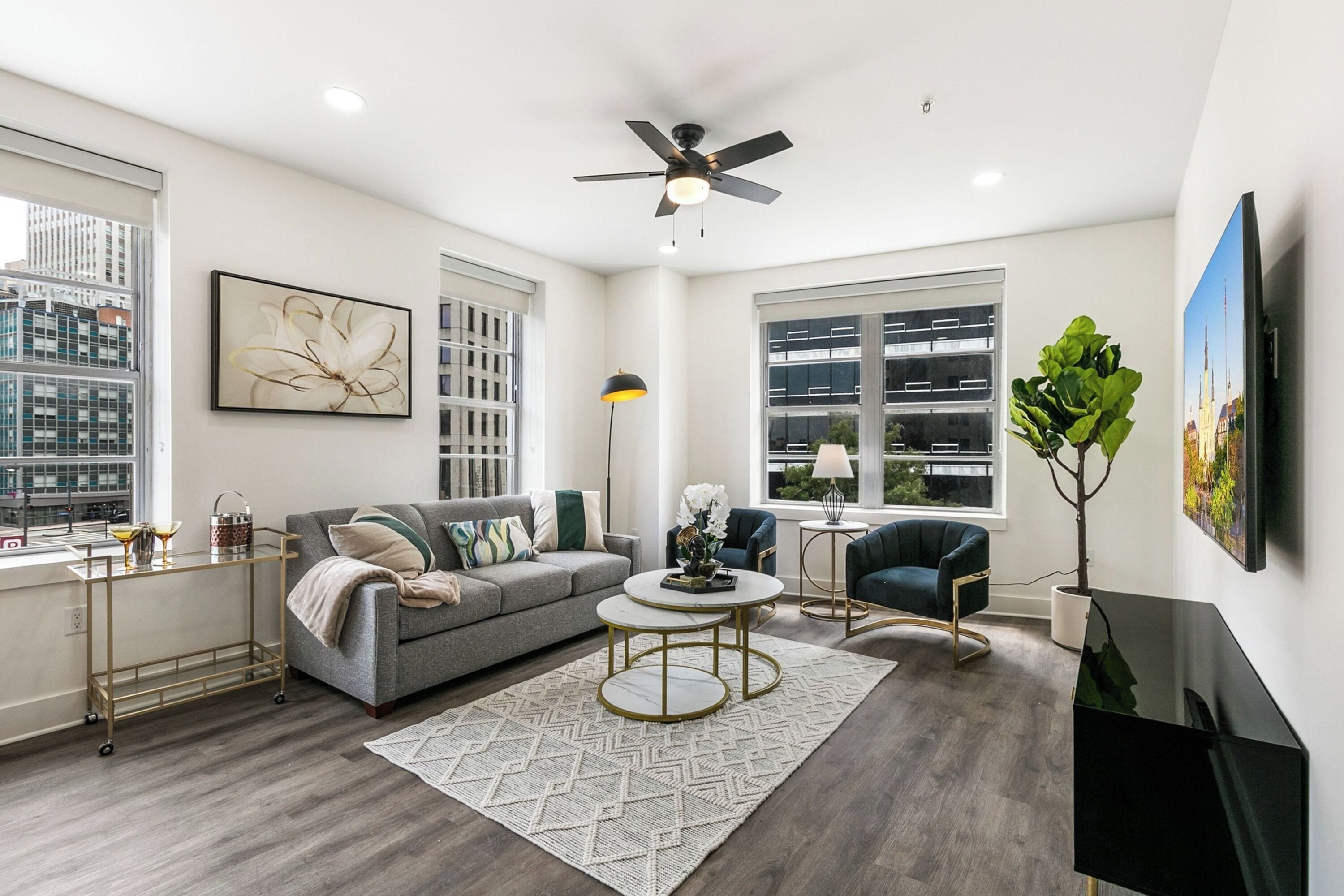 A modern living room with a grey sofa, a coffee table, a TV, and a ceiling fan.
