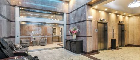 A modern lobby with massage chairs, a reception desk, and two elevators.