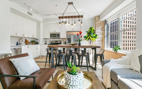 A modern kitchen with white cabinets, a central island, and a hanging light fixture.