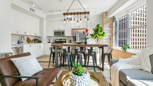 A modern kitchen with white cabinets, a central island, and a hanging light fixture. - California Building (New Orleans)