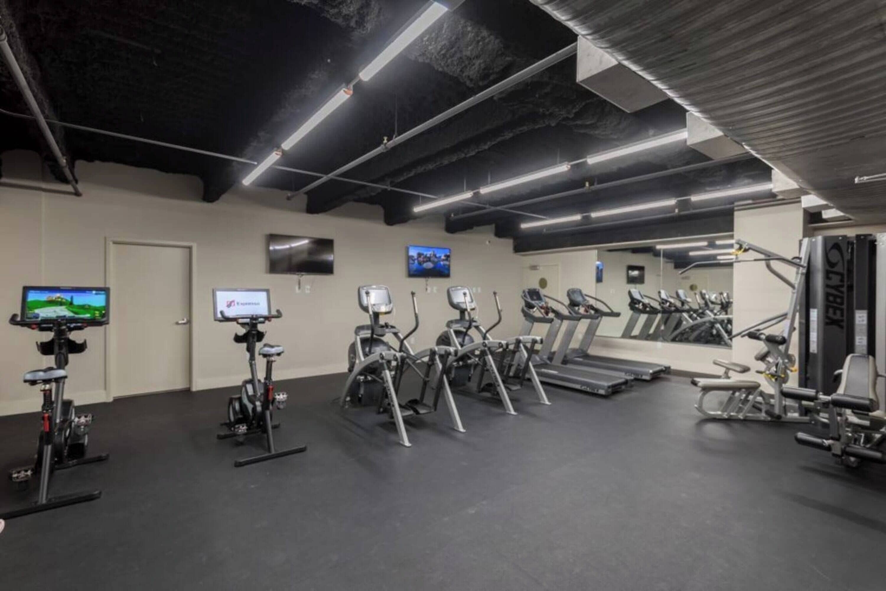 Un gimnasio con bicicletas estáticas, cintas de correr y máquinas de pesas.