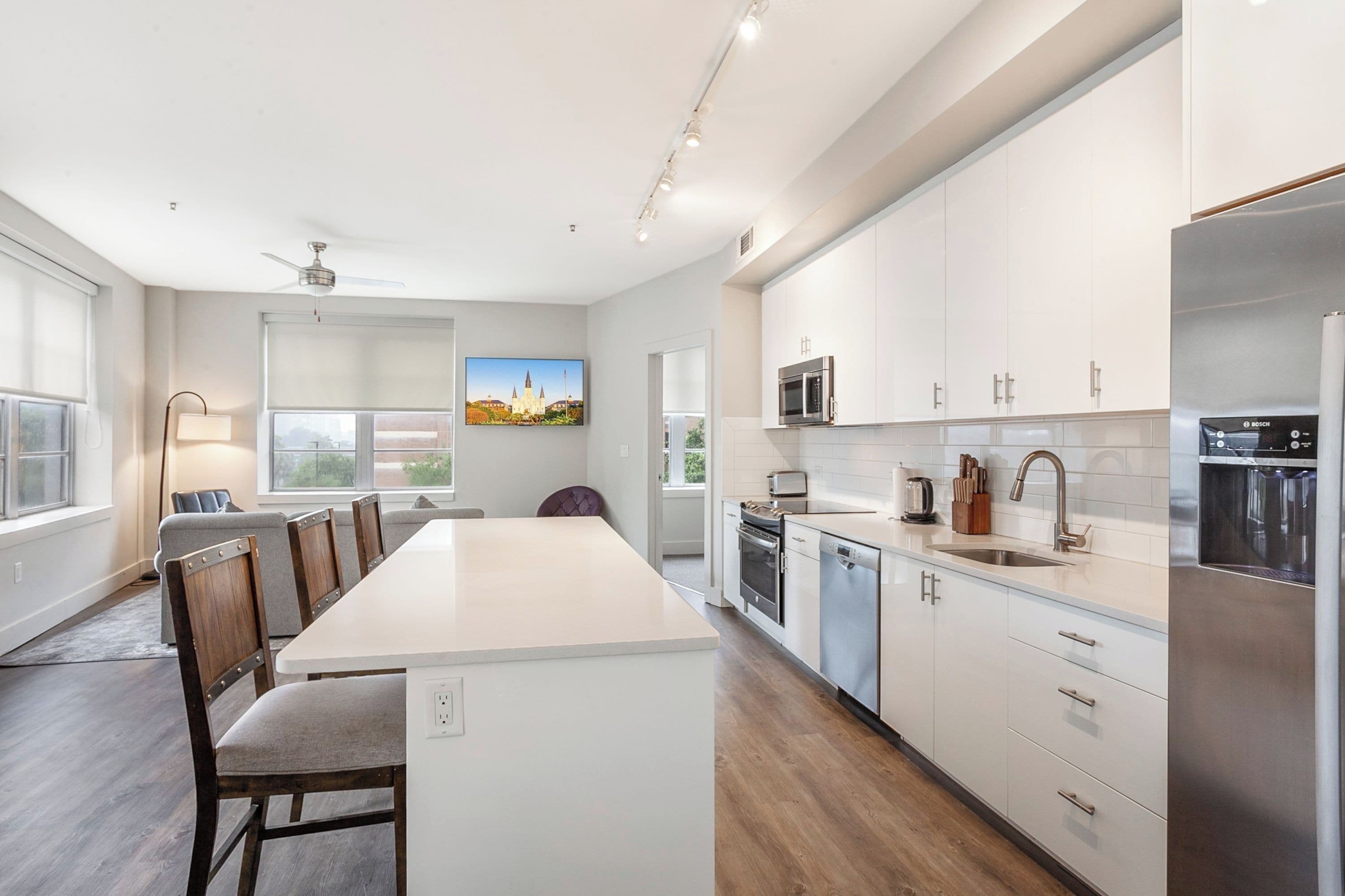 A modern kitchen with white cabinets, stainless steel appliances, and a large island.