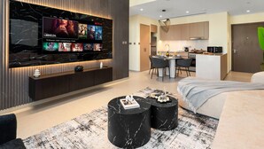 Una sala de estar moderna con televisor grande, comedor y cocina.