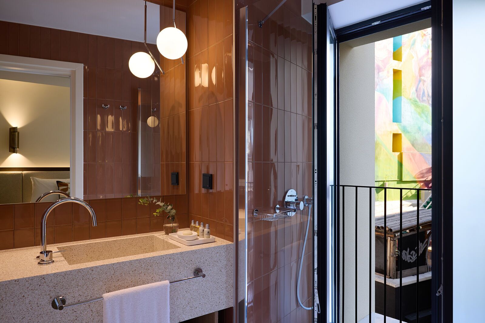 A modern bathroom with a large mirror, a sink with a towel rack, and a shower area.