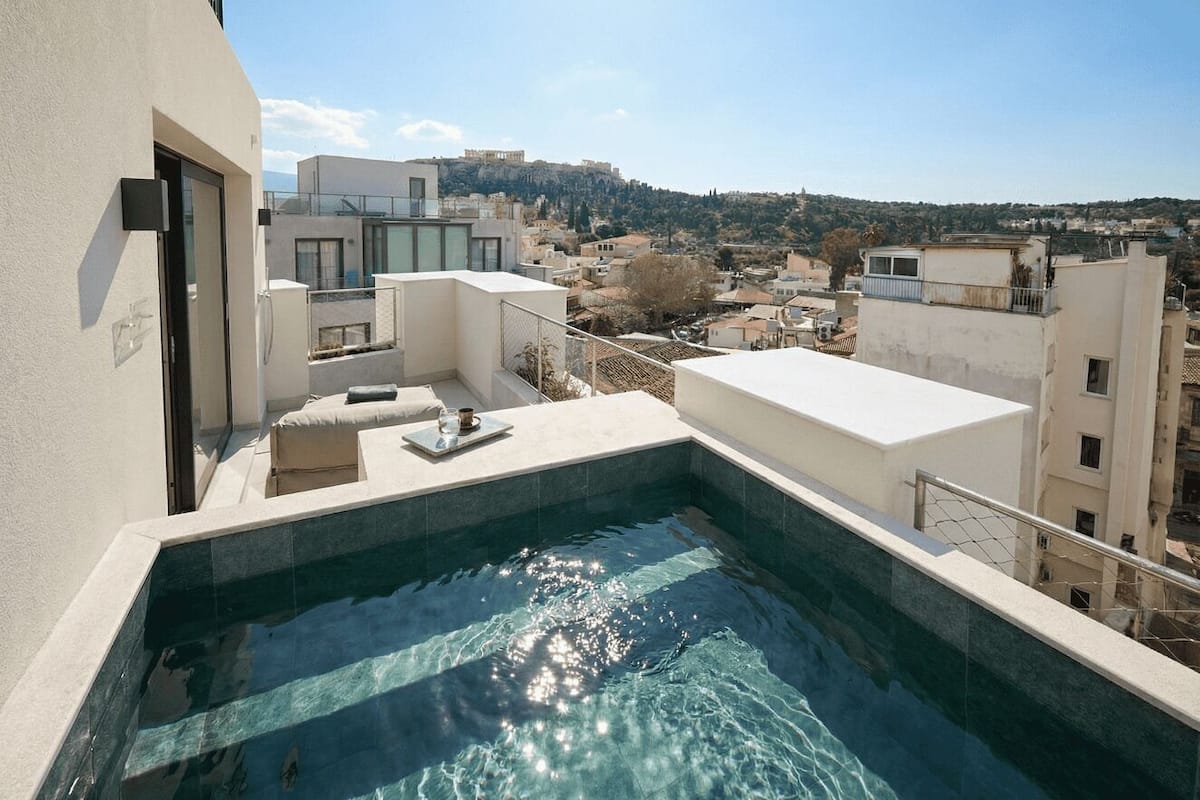 A rooftop swimming pool with a view of the city and a hill in the background.