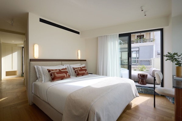 Une chambre d’hôtel moderne dotée d’un grand lit, d’un balcon avec vue et d’un coin salon agrémenté d’une plante.