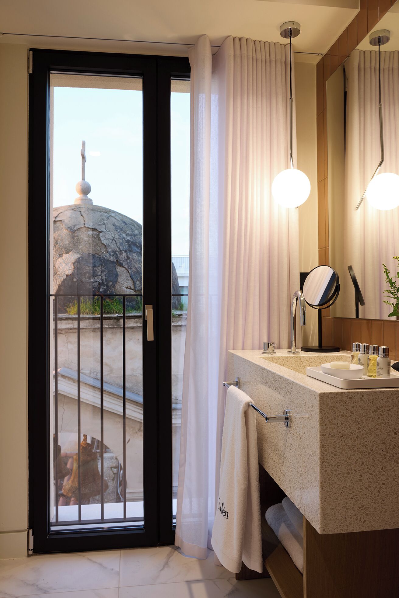 A modern bathroom with a large mirror, a sink, and a towel rack.