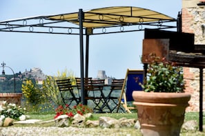Un jardin agrémenté d’une pergola, de chaises et d’une plante en pot.