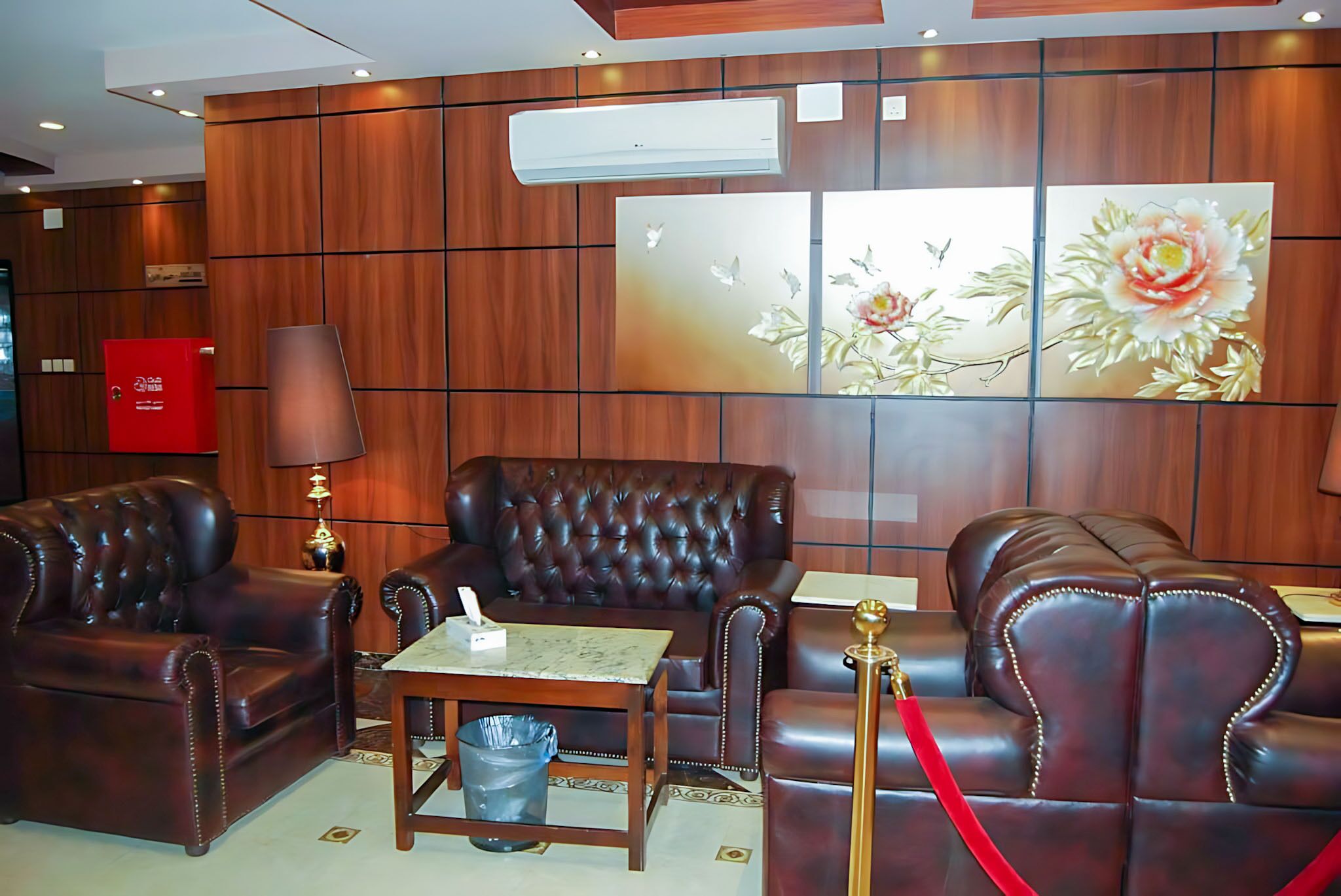 A hotel lobby with leather sofas, a marble table, and a red trash bin.