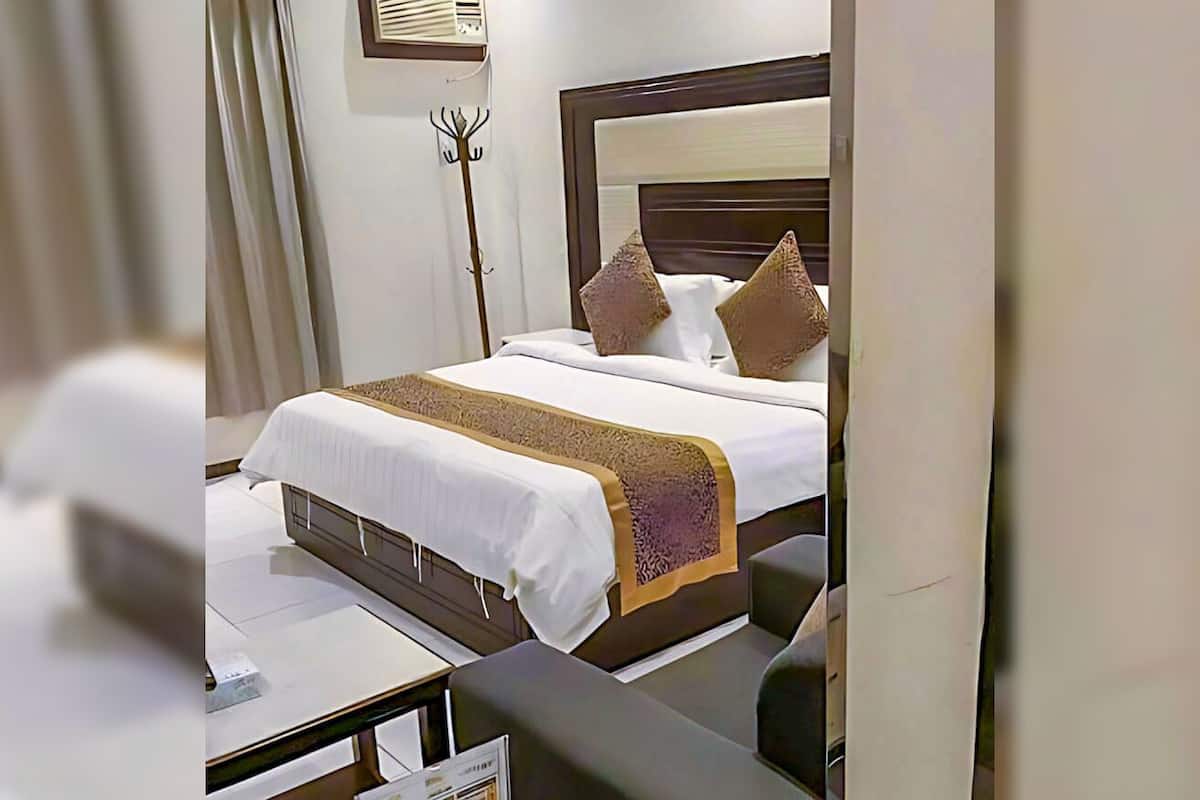 Una habitación de hotel con una cama bien hecha, una mesita de noche con un menú y una lámpara de pie.