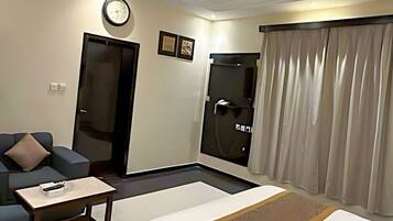 Habitación de hotel con cama, sofá, una mesita, una puerta y zona de ducha.