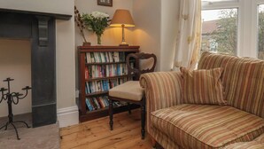 A cozy living room with a fireplace, a bookshelf, a striped sofa, and a lamp. - The Manse (Saltburn-by-the-Sea)