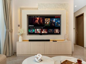 A modern living room with a flat-screen TV mounted on a wall, a wooden console table, and a white vase with dried plants.