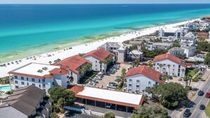 Ein Hotel an der K üste mit mehreren Gebäuden, einem Strand und freiem Blick auf den Ozean.