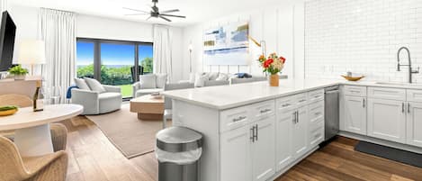 Una cocina moderna con armarios blancos, una isla central y un comedor con vistas.
