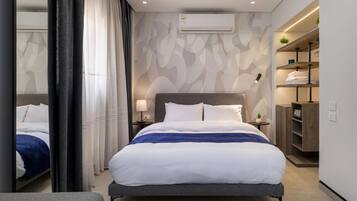 Ein modernes Hotelzimmer mit einem großen Bett, Nachttischen, einer Klimaanlage und einem eingebauten Kleiderschrank.