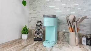 Una cocina con cafetera, especiero y utensilios.