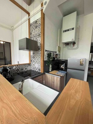 A modern kitchen with a central island, a built-in oven, and a wall-mounted ventilation unit.