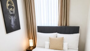 A hotel room with a bed, a nightstand, a lamp, and a wall-mounted artwork.