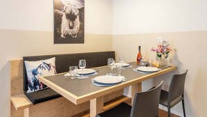 A dining area with a wooden table set for two, a bench with a cushion, and a framed picture on the wall. - Alpin Apartment bei der Bergbahn (Zermatt)