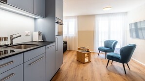A modern kitchen with grey cabinets, a stainless steel sink, and a wooden dining table. - Alpin Apartment bei der Bergbahn (Zermatt)