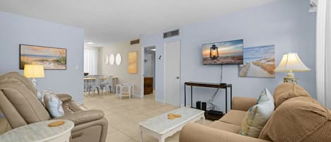 Una sala de estar con sofá, sillón, mesa de centro y un comedor con sillas y una mesa.