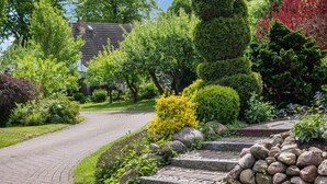 A paved garden pathway leading to a house with a sloped roof. - Cottage 'Haus Am See' with Private Terrace, Private Garden and Wi-Fi (Witzin)