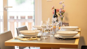 A dining table set with plates, glasses, and cutlery, with a vase of flowers in the background. - Alpin Bijou bei der Bergbahn (Zermatt)