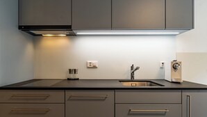 A modern kitchen with a stainless steel sink, a built-in oven, and a range hood. - Alpin Bijou bei der Bergbahn (Zermatt)