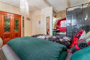 Ein Schlafzimmer mit einem Bett, einem Holzschrank, einer Duschkabine und einer roten Wand mit einem Poster.