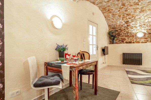 A dining area with a table set for two, a chair, a potted plant, and a radiator.