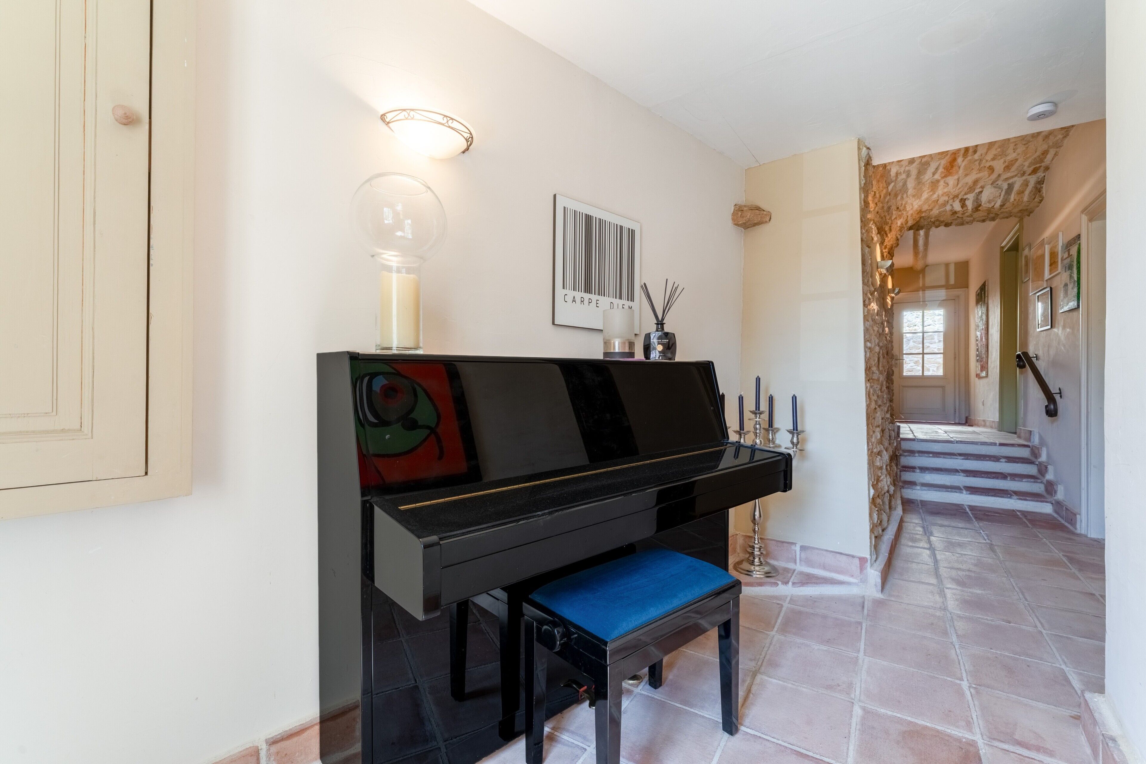 A grand piano in a hallway with a staircase leading to another room.
