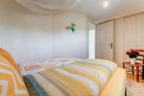 Ein Schlafzimmer mit einem Bett, einem Sessel und einer Blumenvase sowie einer Tür.