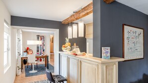 A modern kitchen with a bar area, a dining table with chairs, and a bookshelf. - Gite Bleu - Paradise of Provence (Le Pin)