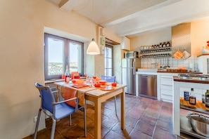 Una cocina con una mesa de comedor, sillas, un refrigerador y un microondas.