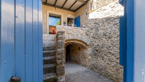 A stone building with a narrow passageway, a blue door, and a staircase leading to an upper level. - Holiday Home 'Orange - Paradis De Provence' with Mountain View, Private Terrace and Wi-Fi (Verfeuil)