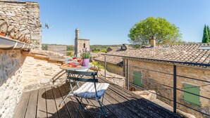 A terrace with a table, chair, and potted plants. - Holiday Home 'Orange - Paradis De Provence' with Mountain View, Private Terrace and Wi-Fi (Verfeuil)