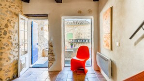 A room with a stone wall, a red chair, a door leading outside, and a radiator on the wall. - Holiday Home 'Orange - Paradis De Provence' with Mountain View, Private Terrace and Wi-Fi (Verfeuil)