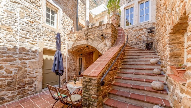 Un escalier en pierre menant à une porte, une table avec des chaises et une plante en pot.