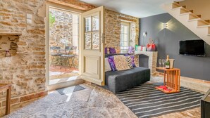 Une pièce aux murs de pierre, avec un canapé, un téléviseur et un escalier.