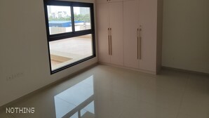 Ein Zimmer mit großem Fenster, Fliesenboden und einem Kleiderschrank mit zwei Türen und Ablage.